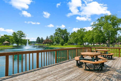 Picnic tables on a wooden deck overlooking a lake at Fairington Apartments in Clarksville, Indiana.