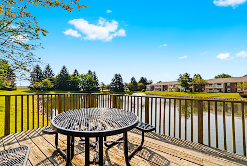 Water fountain in the pond at Fairington Apartments, Anderson, adjacent to a patio with seating overlooking the body of water.