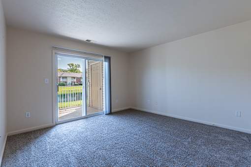 A room with a carpeted floor and a door leading outside.