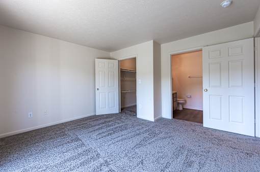 A room with a carpeted floor and three doors.