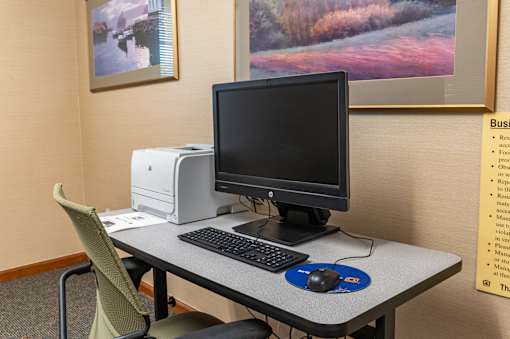 A computer desk with a monitor, keyboard, and mouse.