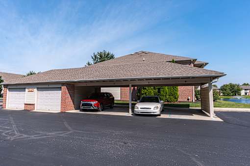 A carport with two cars parked in front of it.