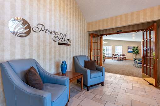 A blue couch and chair are in front of a wall with a logo that says "Preserve Avon".