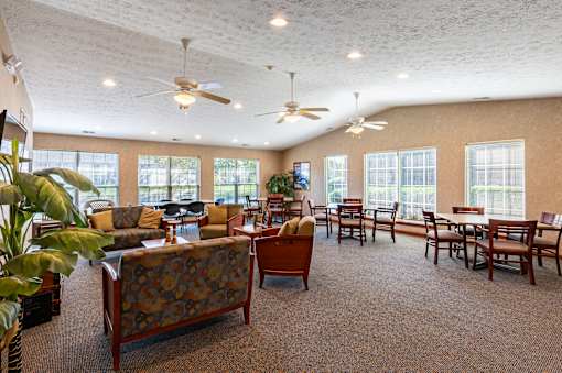 A spacious room with a carpeted floor and a variety of seating options.