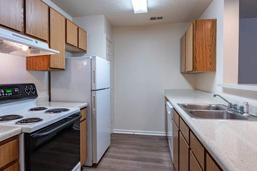 A kitchen with a stove, refrigerator, and cabinets.