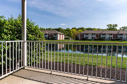 A metal fence in front of a grassy area with apartment buildings in the background.