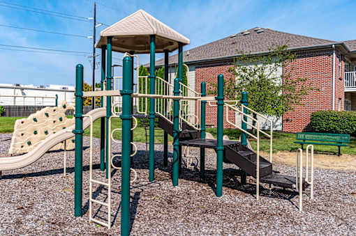 A playground with a green slide and a brown slide.