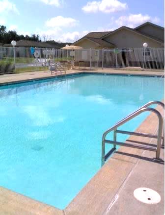 A swimming pool with a metal railing and a wooden deck.