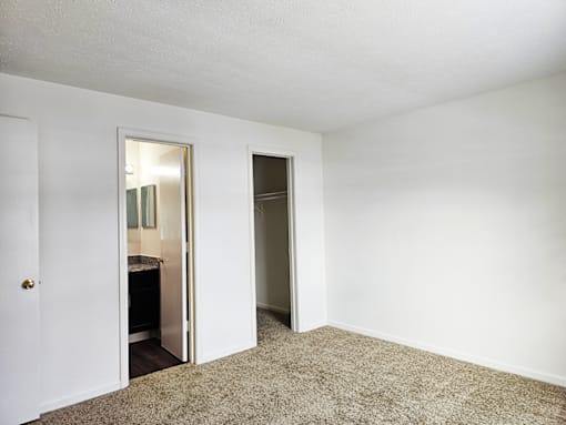 A room with a carpeted floor and two open doors.