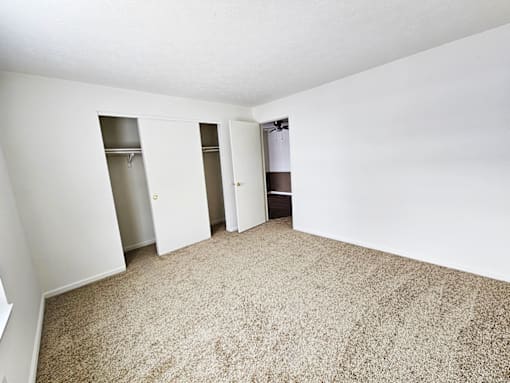 A carpeted room with three closets.