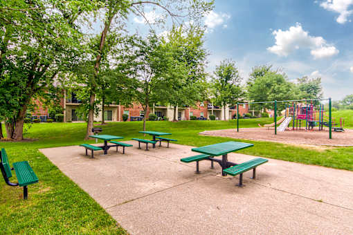 A park with green benches and a playground.