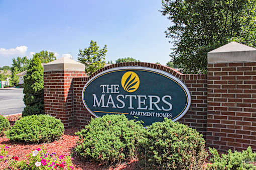 A sign for The Masters Apartment Homes is shown in front of a brick wall.