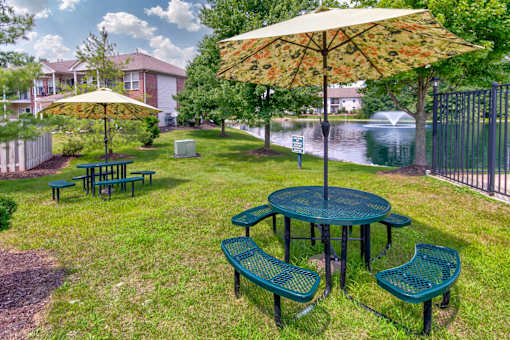 A green picnic table with a yellow umbrella is in the foreground of a park.