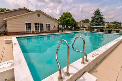 A swimming pool with a diving board and a building in the background.