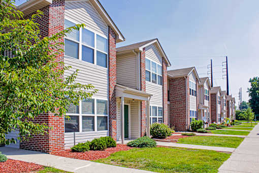 A row of houses with a tree in front of the first one.