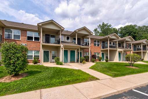 Apartment complex with green lawns and trees in the background.