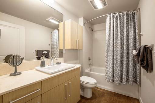 Bathroom with wood vanity and tub shower combo at The Lyric Apartments, Seattle, 98102