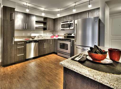 Modern kitchen with stainless steel appliances and granite counters at The Lyric Apartments, Seattle, WA 98102