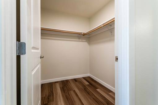 Walk-in closet with hardwood flooring and hanging rods at The Lyric Apartments, Washington