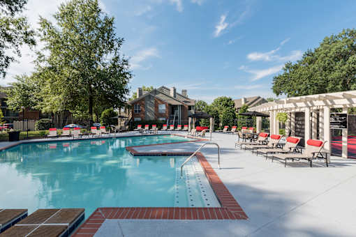A large outdoor swimming pool surrounded by red lounge chairs.