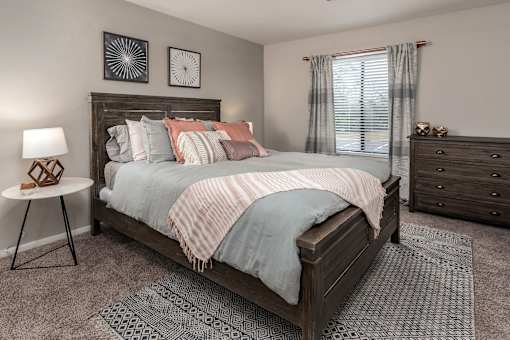 A bedroom with a bed, nightstand, and window.