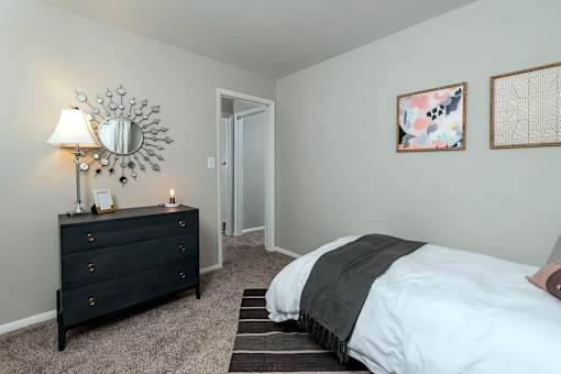 A bedroom with a bed, dresser, and two pictures on the wall.