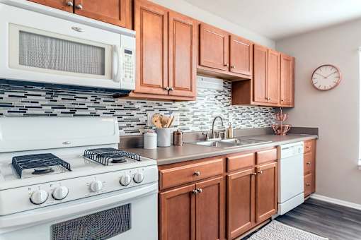 A kitchen with a white stove, white microwave, and wooden cabinets.