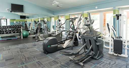 A gym with a variety of equipment including treadmills, weights, and exercise machines.