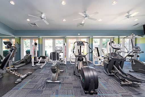 A gym with a variety of exercise equipment including treadmills, stationary bikes, and elliptical machines.