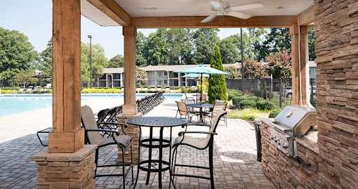 A patio with a table and chairs and a grill.