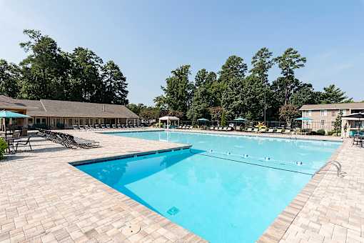 A large swimming pool surrounded by trees and a building.