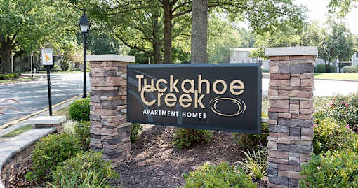 A sign for Tuckahoe Creek Apartment Homes is displayed in front of a landscaped area.
