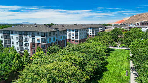 A row of apartment buildings with green trees in the foreground.