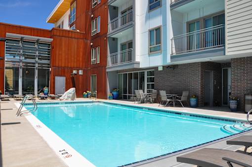 A swimming pool in front of a building with a red and white striped wall.