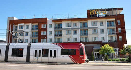 A red and white train is in front of a building with a sign that says "BROAD".