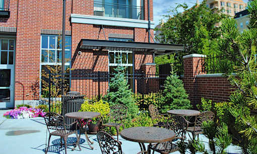 Liberty Gateway Apartments, Salt Lake City, Utah, a patio with a table and chairs is surrounded by green plants.