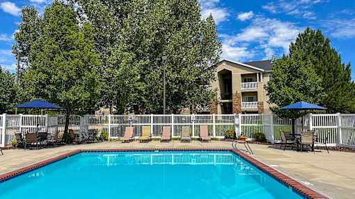 A swimming pool surrounded by a white fence and trees.