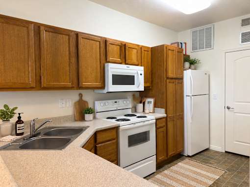 Liberty Landing Apartments, West Jordan, UT, kitchen with wooden cabinets and white appliances.