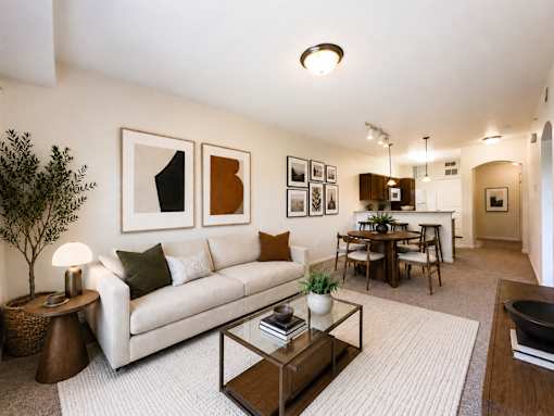 Liberty Landing Apartments, West Jordan, UT, A living room with a white couch, a coffee table, and a dining table with chairs.