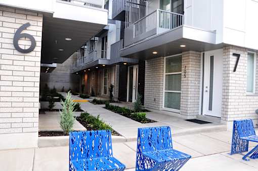 Two blue benches are in front of a building with the numbers 6 and 7 on it. at Liberty Square Apartments - Saltlake City, UT Apartments, Saltlake City, Utah