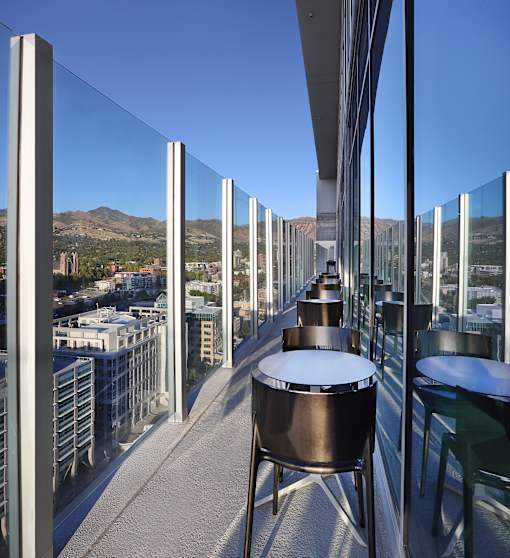 A glass balcony with metal railings and a table and chairs set up on it.