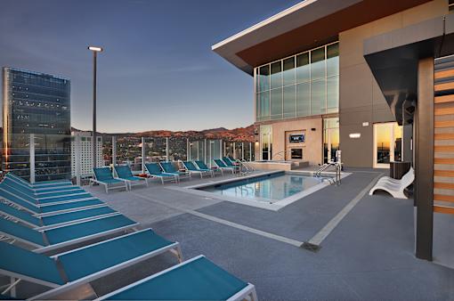 A modern building with a pool and lounge chairs.