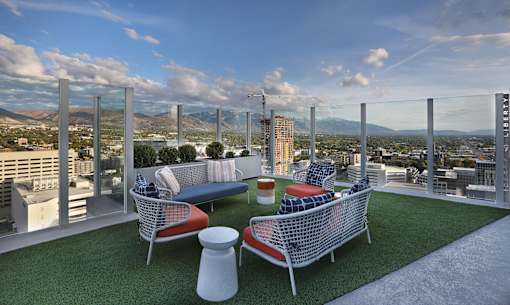 A rooftop patio with a couch, chairs, and a table.