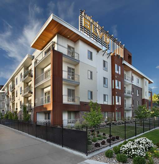 Liberty Blvd Apartments, Salt Lake City, Utah, A modern apartment building with a black fence and green bushes in front.