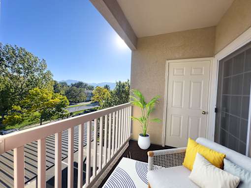 A balcony with a white couch and a potted plant.