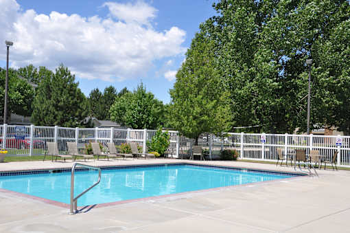 A pool surrounded by a white fence and trees.