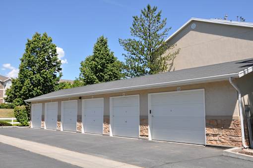 A row of white garage doors in front of a building.