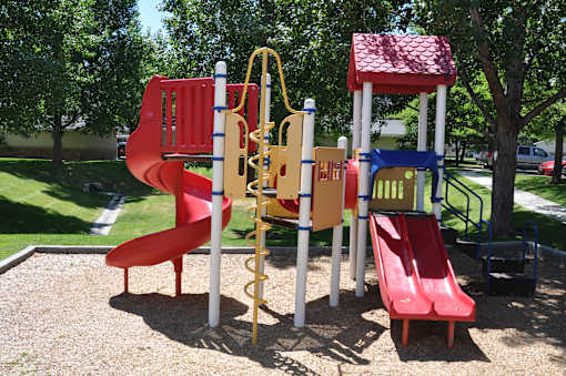 A playground with a red slide and a yellow and blue structure.
