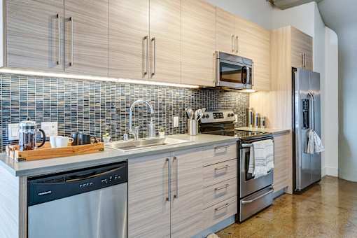 gorgeous modern kitchen in Maxfield loft with light wood cabinets, modern fixtures, updated appliances, and beautiful blue tile backsplash