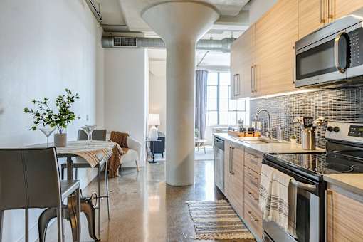 gorgeous modern kitchen in Maxfield loft with light wood cabinets, modern fixtures, updated appliances, and beautiful blue tile backsplash